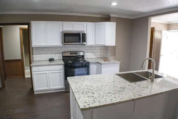 a kitchen with granite countertop a sink and stainless steel appliances
