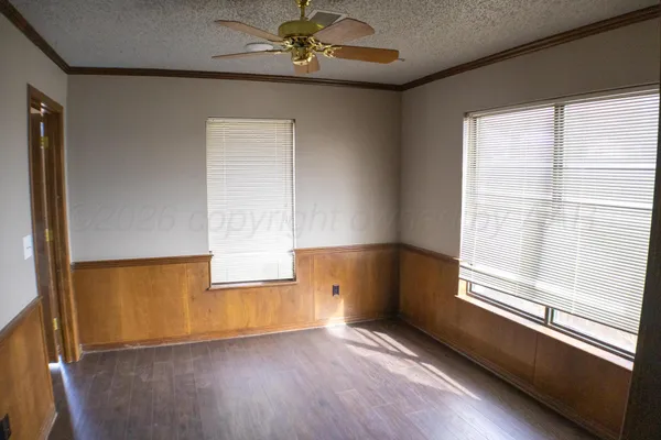 a view of an empty room with a window and wooden floor