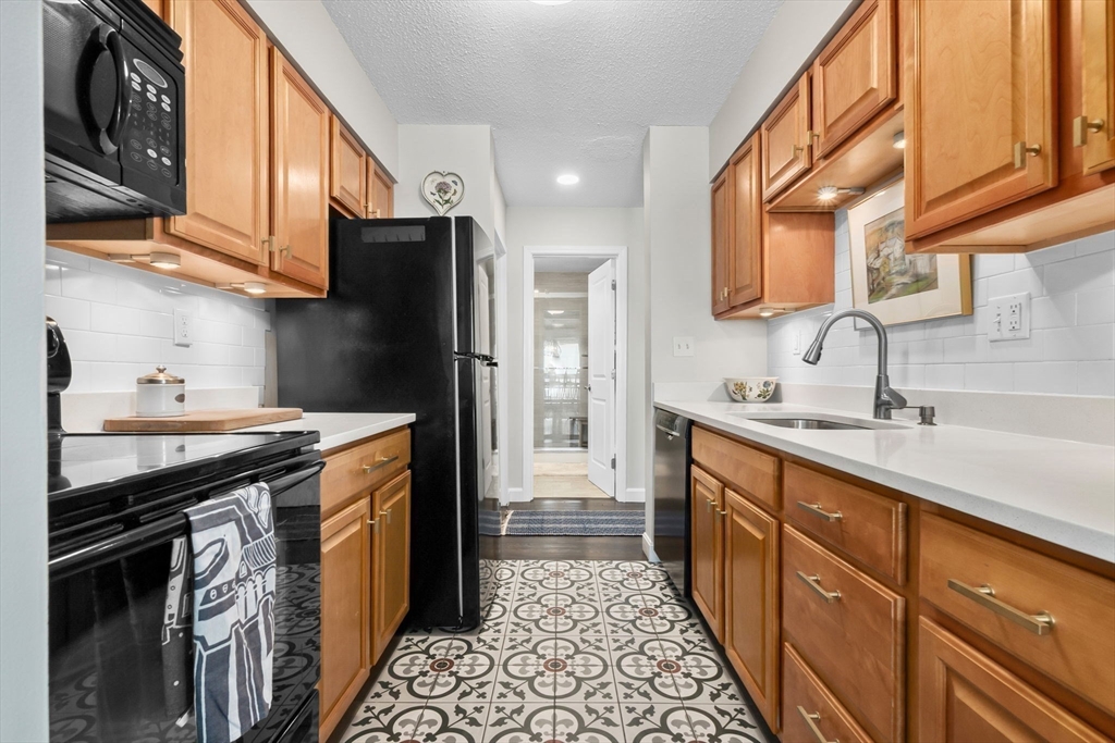 117 Water Street, Unit 28 Beverly, MA 01915 - Photo 12 of 35 a kitchen with stainless steel appliances granite countertop a sink stove and refrigerator