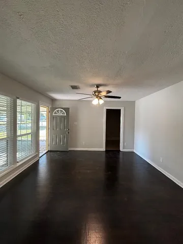 an empty room with wooden floor chandelier and windows