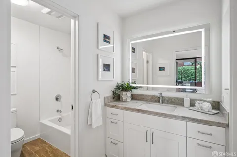 a bathroom with a double vanity sink toilet mirror and bathtub