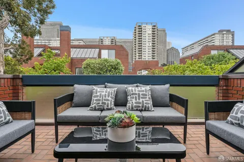 a roof deck with couch and a potted plant