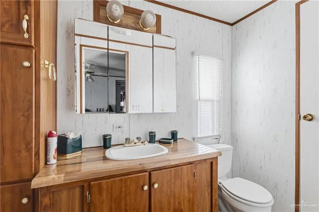 a bathroom with a granite countertop sink toilet and mirror