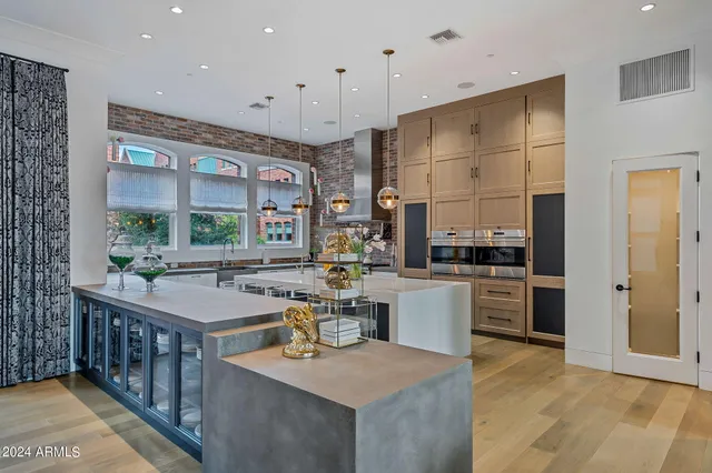 a spacious bedroom with a large bed a chandelier and windows