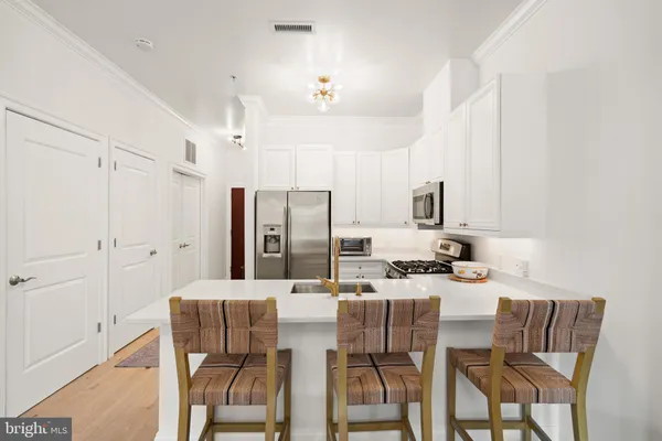 a kitchen with stainless steel appliances kitchen island granite countertop a dining table chairs and a refrigerator