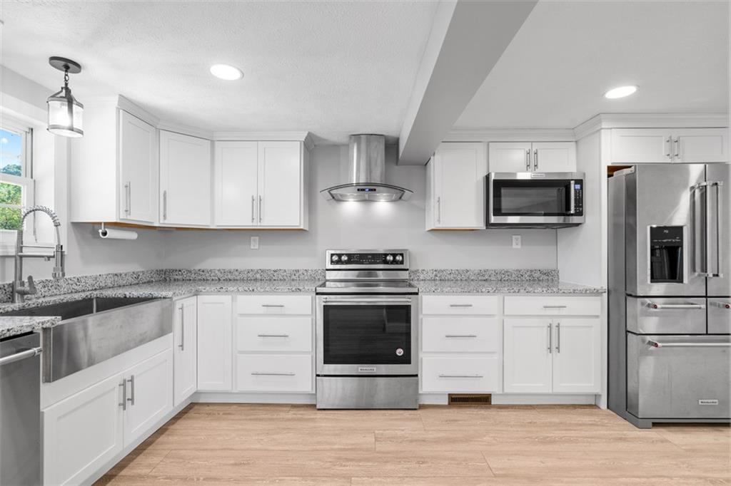 428 Weimer Road Leechburg, PA 15656 - Photo 4 of 42 a kitchen with stainless steel appliances granite countertop a stove top oven a refrigerator and white cabinets with wooden floor