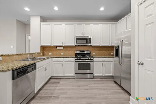 a kitchen with granite countertop white cabinets and stainless steel appliances