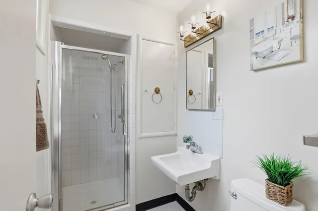a bathroom with a sink a mirror a potted plant and a shower
