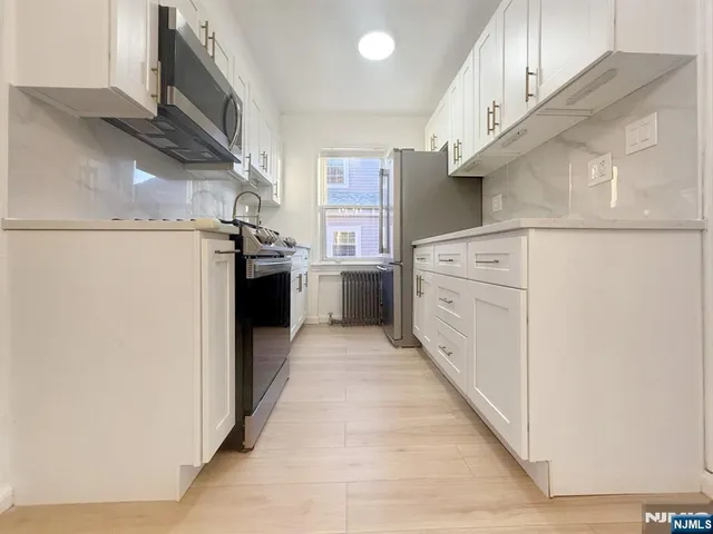 a kitchen with stainless steel appliances granite countertop a refrigerator a stove and a sink