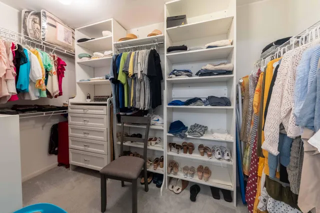 a view of walk in closet with clothes and shoes