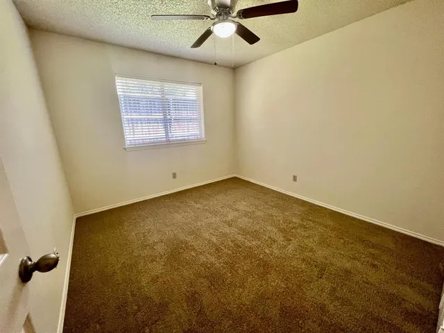 an empty room with a window and a ceiling fan