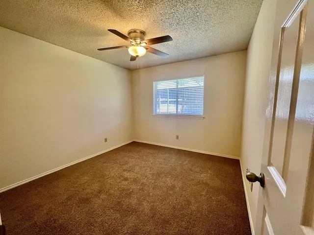 an empty room with windows and fan