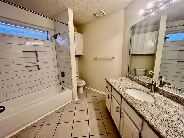 a bathroom with a granite countertop sink a toilet and shower