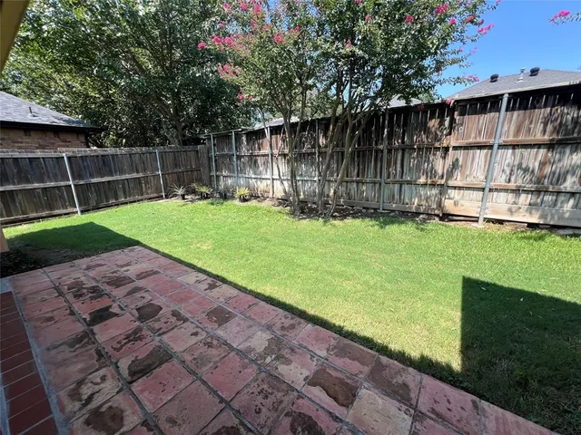 a view of a backyard with wooden fence and large trees