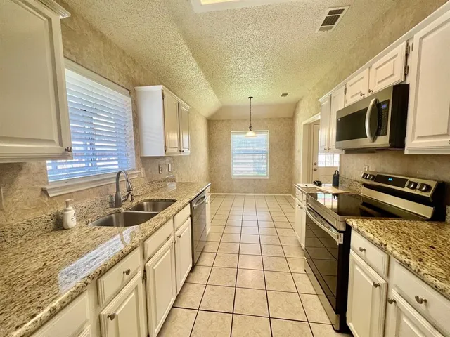 a kitchen with stainless steel appliances granite countertop a stove a sink and a microwave