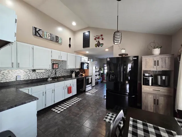 a open kitchen with stainless steel appliances granite countertop a refrigerator a stove and a sink