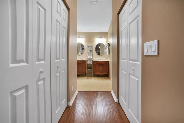 a view of a hallway with wooden floor and a bathroom