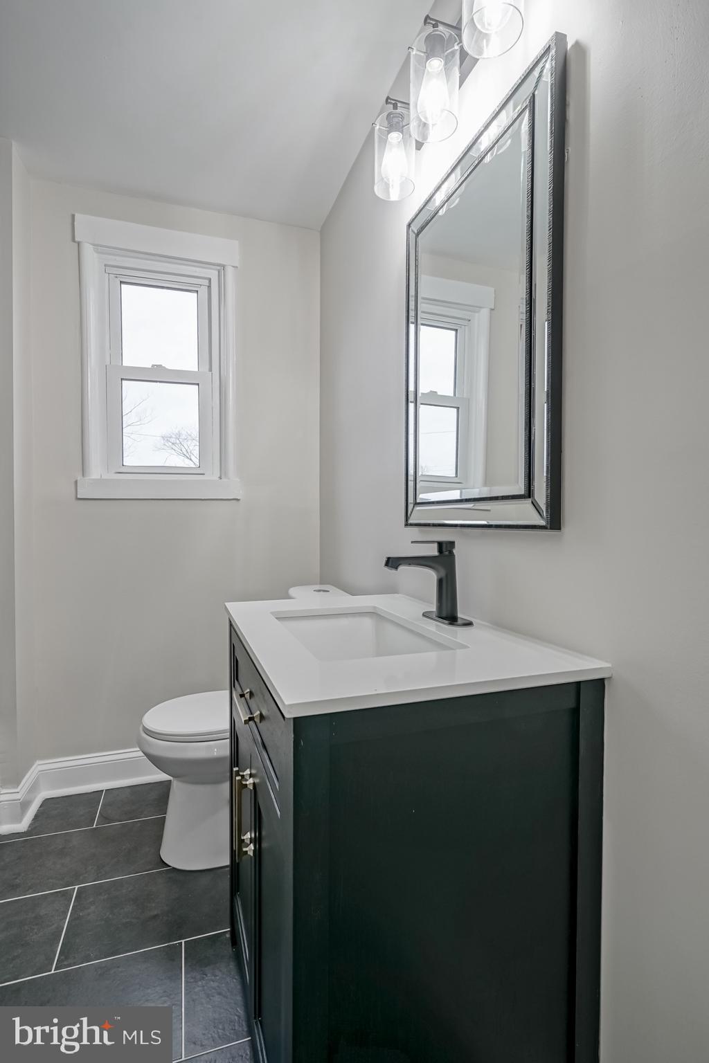 2863 Cushing Road Camden, NJ 08104 - Photo 17 of 33 a bathroom with a toilet a sink a mirror and a window