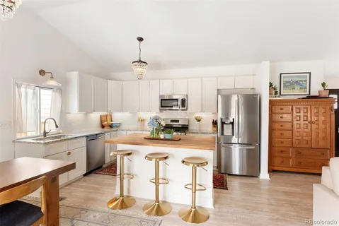 a kitchen with granite countertop a refrigerator stove top oven and sink