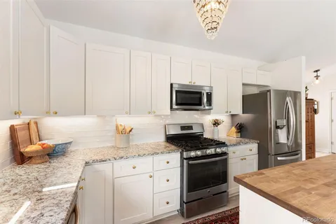 a kitchen with granite countertop a sink stainless steel appliances and white cabinets