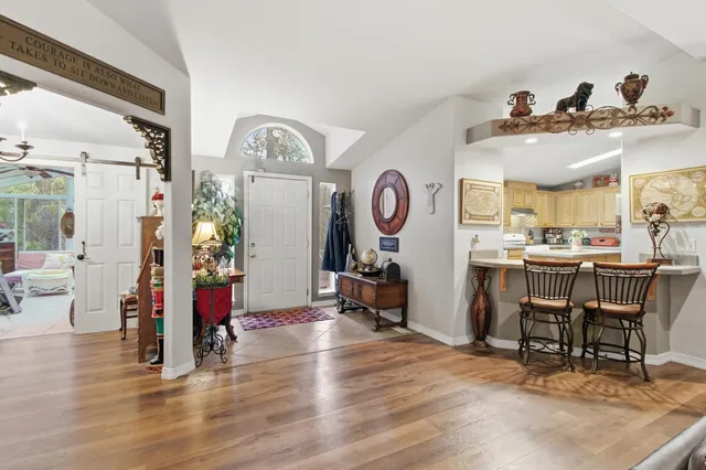 a kitchen with stainless steel appliances granite countertop a refrigerator a stove top oven a sink dishwasher and dining table with wooden floor