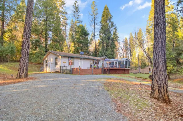 a front view of a house with a yard and large tree