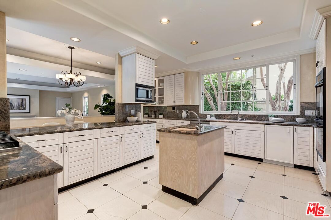 110 North Oakhurst Drive Beverly Hills, CA 90210 - Photo 11 of 29 a kitchen with granite countertop white cabinets white appliances a large window and a sink