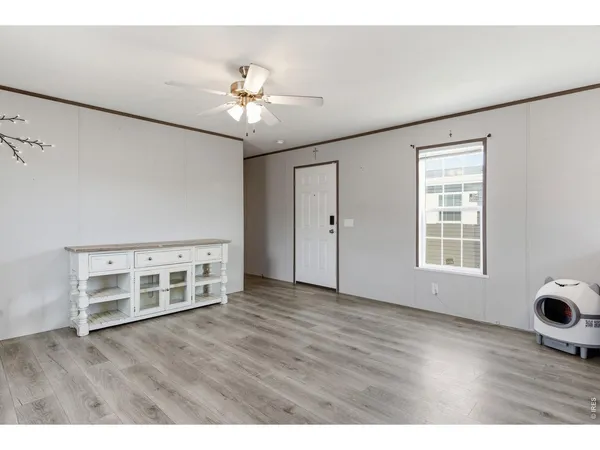 a view of an empty room with wooden floor and a window