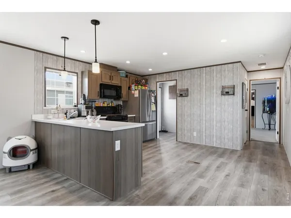 a kitchen with stainless steel appliances granite countertop a refrigerator a sink a stove and a wooden floors