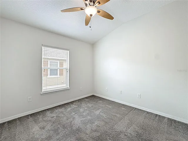 an empty room with a chandelier fan and windows