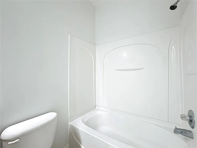 an empty room with a chandelier fan and windows