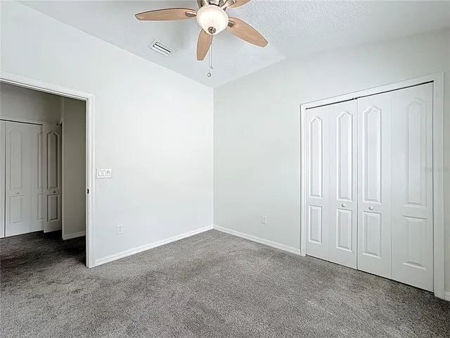 an empty room with windows and ceiling fan