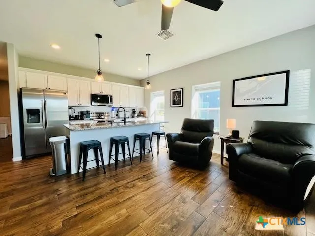 a living room with stainless steel appliances furniture and a kitchen view