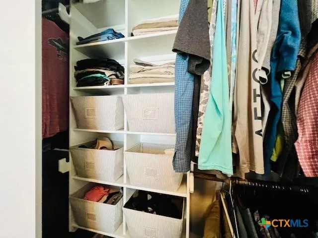a view of walk in closet with clothes and shoes