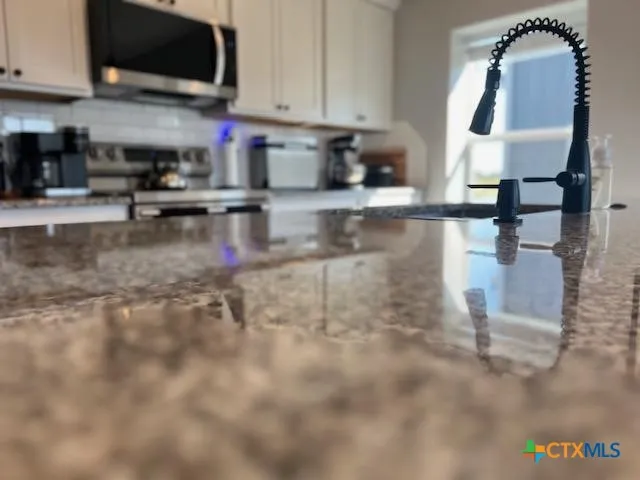 a kitchen with stainless steel appliances granite countertop a sink a stove and a microwave