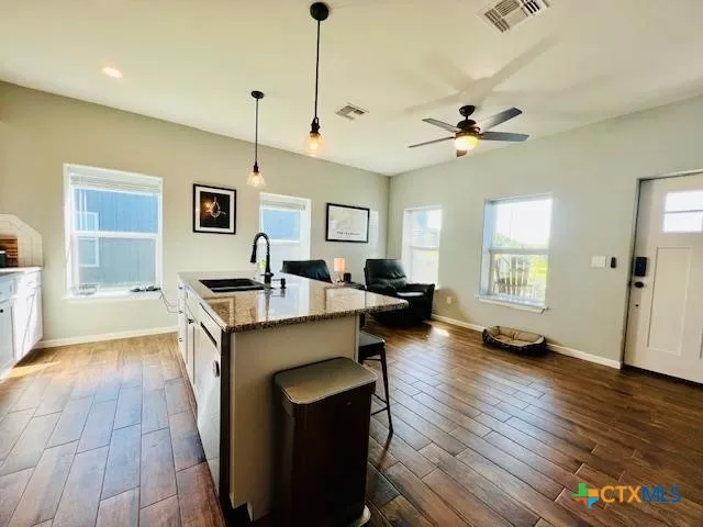 a living room with couches a flat screen tv and kitchen view