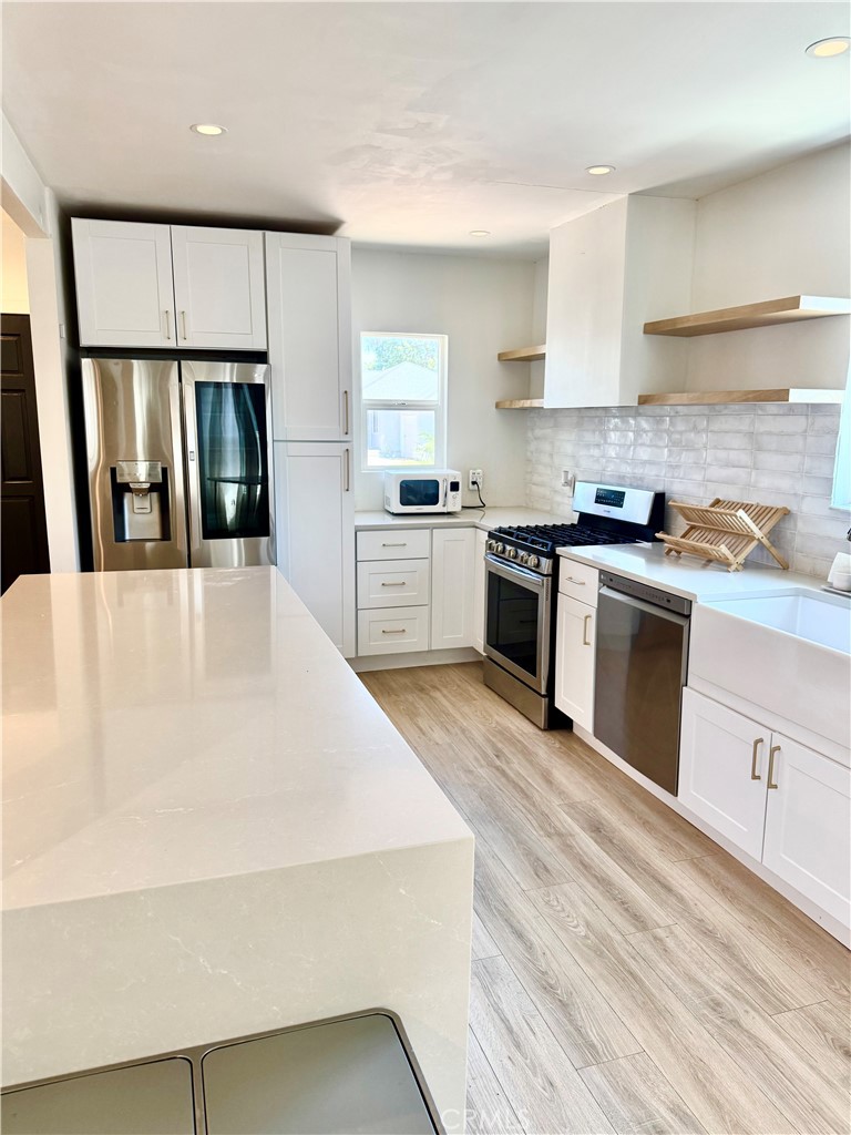18913 Haas Avenue Torrance, CA 90504 - Photo 1 of 20 a large kitchen with granite countertop a stove top oven a sink dishwasher and white cabinets with wooden floor