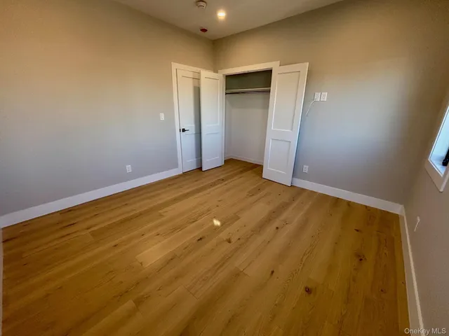a view of empty room with window and wooden floor