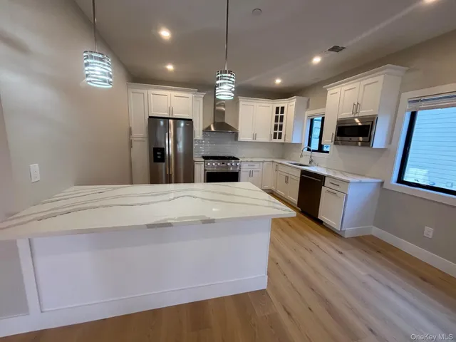 a large kitchen with kitchen island a stove a sink dishwasher and a refrigerator with wooden floor