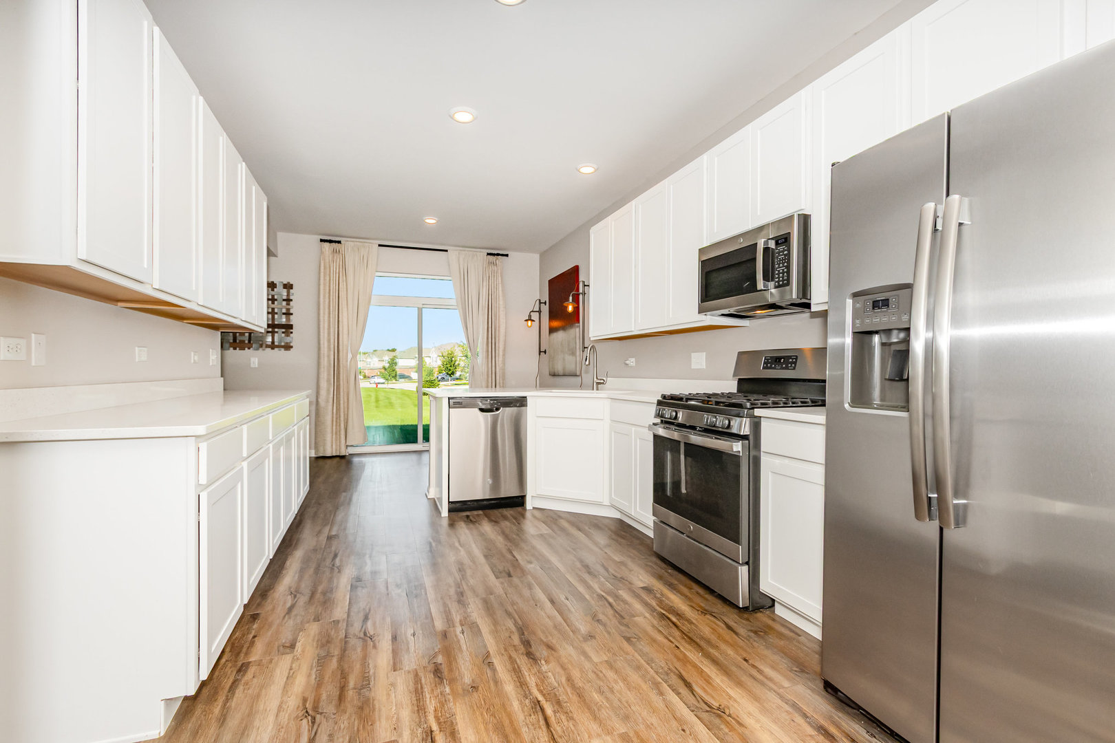 24724 McCormick Way Manhattan, IL 60442 - Photo 10 of 24 a kitchen with stainless steel appliances a refrigerator a sink dishwasher a oven with white cabinets and wooden floor
