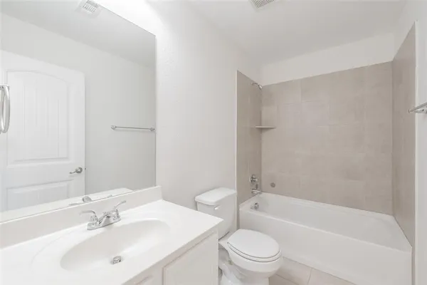 a bathroom with a bathtub shower sink vanity mirror and toilet