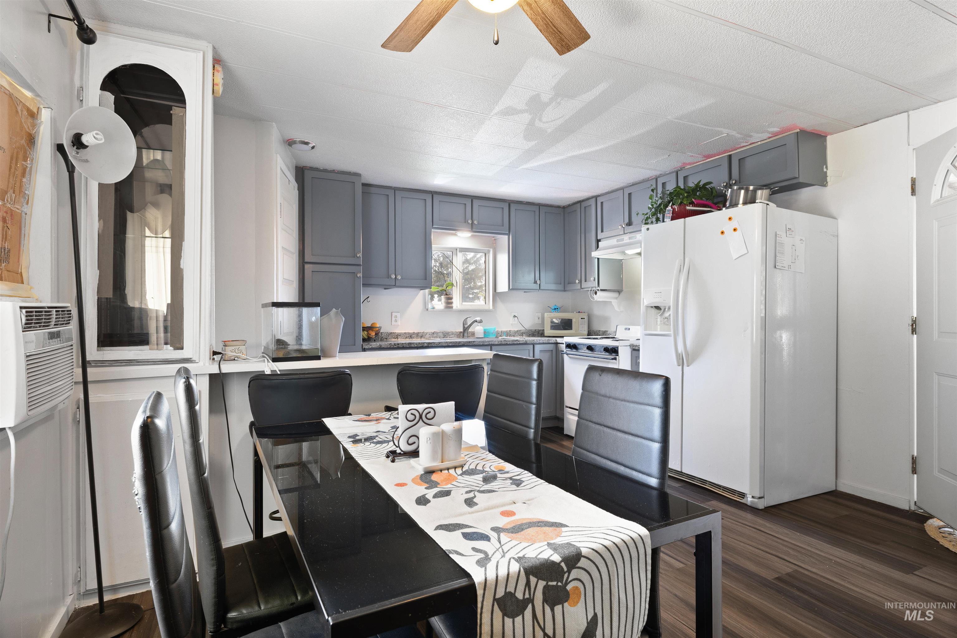 198 South Hills Road, Unit 65 Twin Falls, ID 83301 - Photo 4 of 16 Kitchen and dining area featuring wood-finish flooring, grey cabinetry, white appliances, and a ceiling fan with light fixture