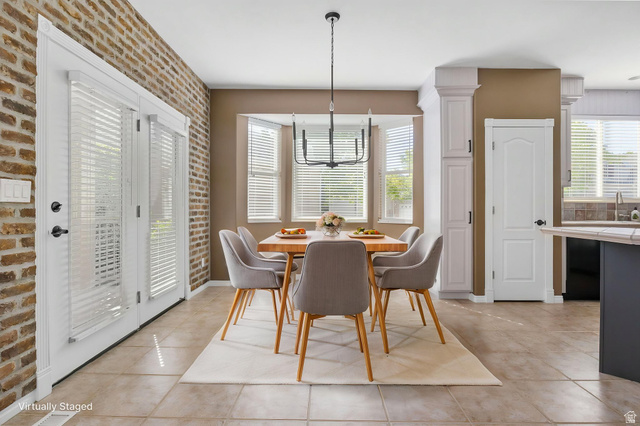 1417 Blacksmith Lane Draper, UT 84020 - Photo 13 of 57 Dining area featuring a bay window, tile flooring, brick accent wall, and a modern chandelier