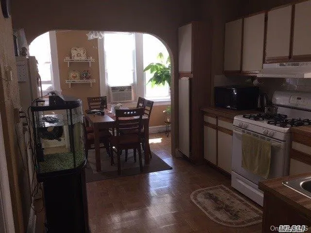 a kitchen with stainless steel appliances granite countertop a stove a refrigerator a sink a dining table and chairs with wooden floor