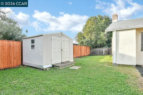 a view of a backyard with barn plants and large tree