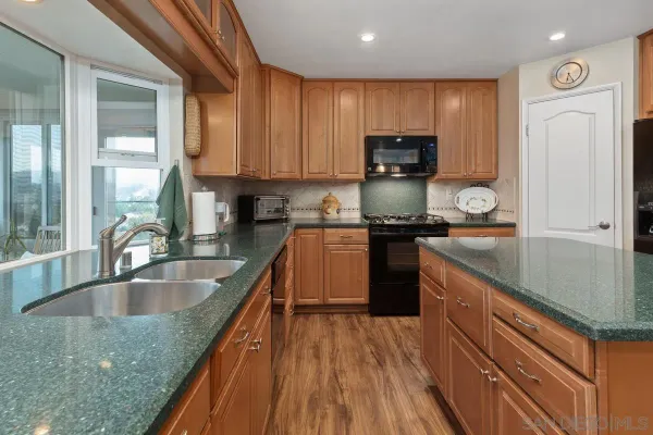 a kitchen with kitchen island granite countertop a sink dishwasher stove and refrigerator with wooden floor