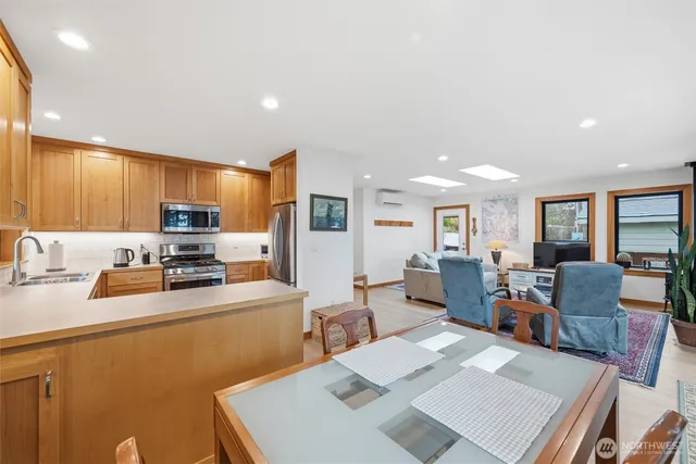 a living room with stainless steel appliances furniture a rug and a kitchen view