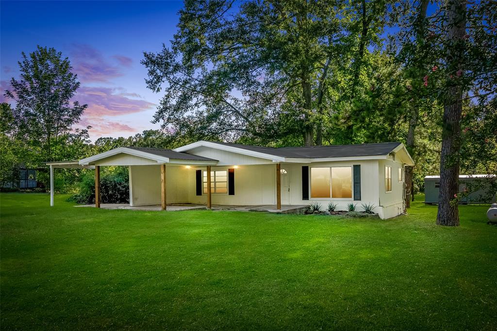 Back of property at dusk with a lawn and covered porch