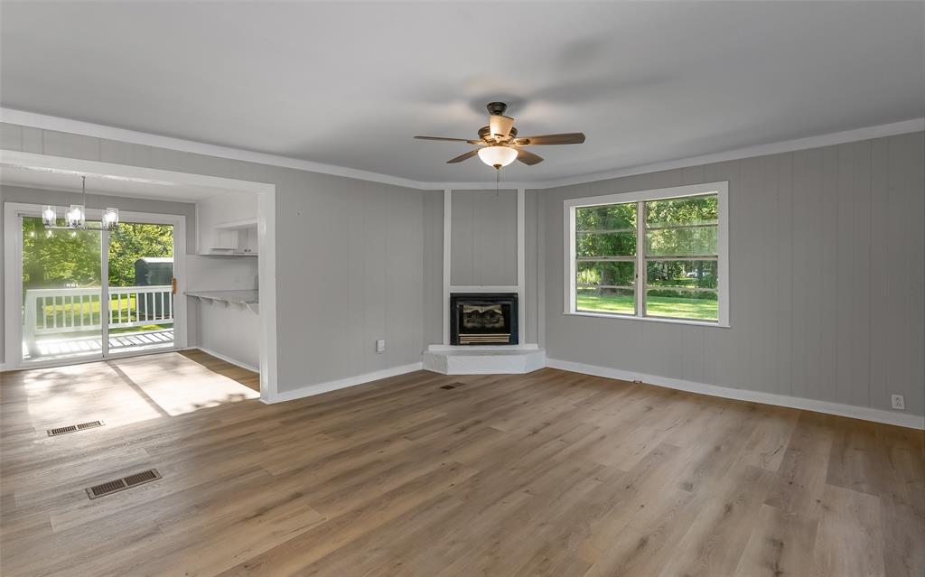 224 Prysock Road Doyline, LA 71023 - Photo 3 of 39 Unfurnished living room with light wood-style floors, a glass covered fireplace, ceiling fan, ornamental molding, and a chandelier