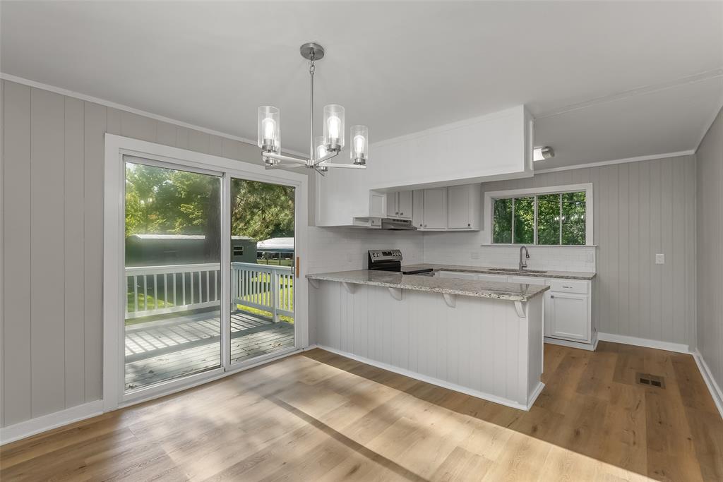 224 Prysock Road Doyline, LA 71023 - Photo 7 of 39 Kitchen with wood walls, decorative backsplash, white cabinetry, pendant lighting, and light stone counters